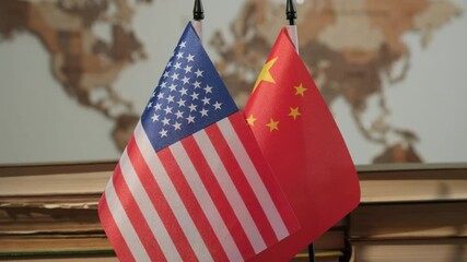 American and Chinese flag on desk with books in office on background of world map on wall