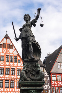 The Fountain of Justice statue in Frankfurt's Romerberg square, with Lady Justice and traditional half timbered buildings in the background.