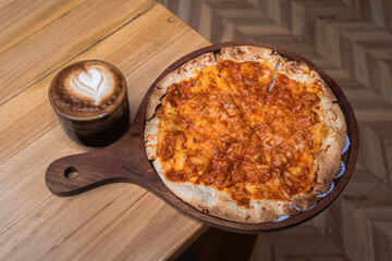 Delicious tuna pizza and hot latte coffee at cafe table.