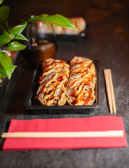 A beautiful sushi tray with chopsticks and a red napkin