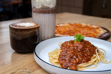 Hot latte coffee and tuna pizza at cafe table. Tiramisu frappe. Milkshake. 