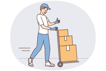 Man at warehouse worker carries cargo cart with cardboard boxes and shows thumbs up