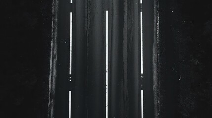 Aerial view of a dark asphalt road with white lines marking lanes.