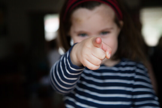 Happy little girl pointing at camera focus on finger