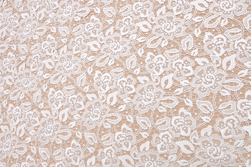 White bridal lace on skin color background. Flatlay featuring bridal textile ideal for wedding creations, with soft white lace.