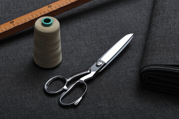 Professional sewing scissors rest atop a bolt of deep blue denim fabric, representing craftsmanship, fashion tailoring, and precision in garment-making.