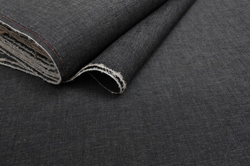 Top down view of a grey bolt of denim fabric, representing craftsmanship, fashion tailoring, and precision in garment-making.