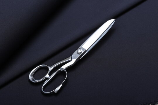 Professional sewing scissors rest atop a bolt of deep blue denim fabric, representing craftsmanship, fashion tailoring, and precision in garment-making.