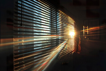 A bright ray of sunlight makes its way through the blinds into a dark room of a city apartment.