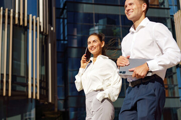 Business professionals enjoy a sunny day as they walk confidently near a modern urban building
