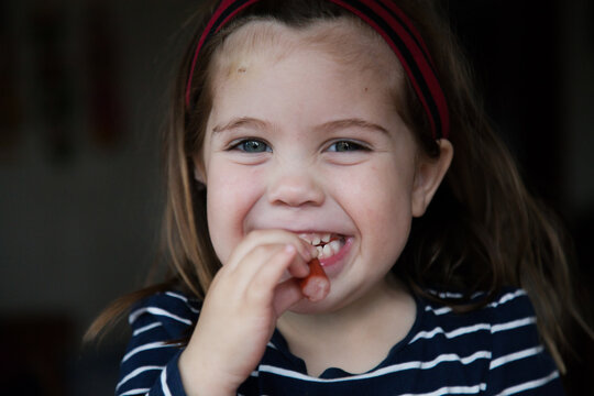 Happy child eating frankfurt sausage and looking at camera