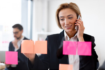 Professional woman wearing formal attire engages in communication, managing priorities using sticky...