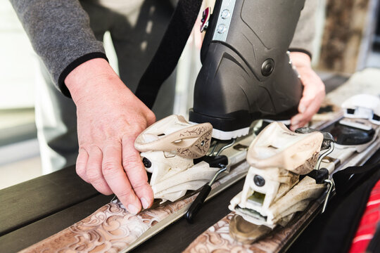 man adjusting bindings on skis