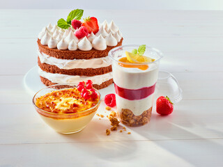 Sahnetorte mit Tupfern Schokoladen Bisquit Boden und Erdbeeren dazu Quark Desserts gechichtet mit Erdbeeren auf hellem Holzfond, Dessert, Creme brulee, 