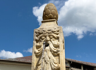 Ornate stone fountain with classical face design under blue sky