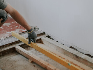A young man measures the space for a fireplace using a building level.