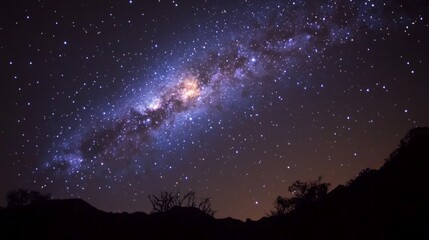 A starry night sky with a long, thin cloud of gas and dust called a nebula