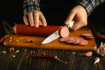 Hands deftly slice through a log of homemade sausage on a wooden cutting board, surrounded by fresh...