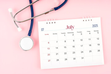 July 2025 desk calendar and stethoscope, Medical appointment schedule to check up.
