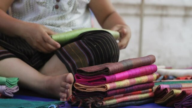 Thai vendor folding silk Sunday market, Chiang mai Thailand 