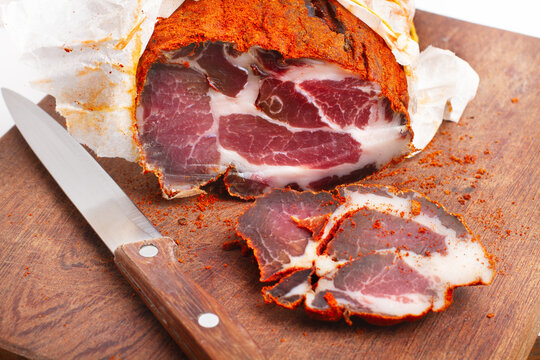 A piece of bondiola with a knife on a wooden kitchen board