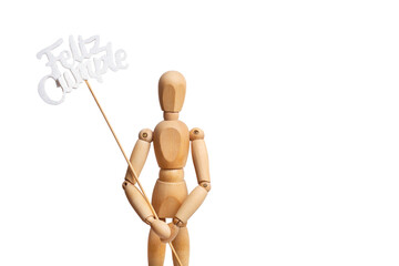 A wooden toy mannequin holding a feliz cumpleaños sign in his hand on white background (trad. happy birthday)