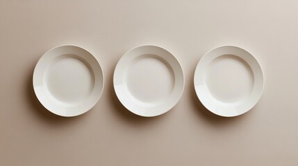 A minimalist arrangement of three white plates, placed evenly side by side, top view on a neutral surface 