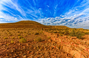 Cloudscape and landscape with barren rocky hill and an old long stone boundary wall the Biedouw Valley in the northern Cederberg, South Africa