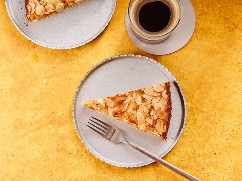 Slice of Almond Cake Served on a Plate With Coffee on a Vibrant Yellow Background