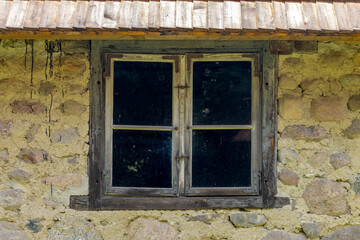 Window in the wall of a stone house in the village