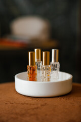 Liquid fragrances in glass bottles in white ceramic tray in room close up. Home cozy atmosphere.