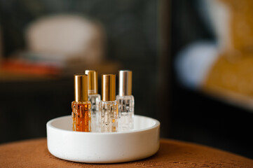 Liquid fragrances in glass bottles in white ceramic tray in room close up. Home cozy atmosphere.