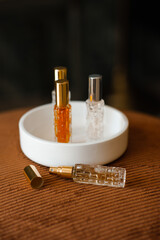 Liquid fragrances in glass bottles in white ceramic tray in room close up. Home cozy atmosphere.