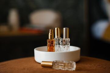 Liquid fragrances in glass bottles in white ceramic tray in room close up. Home cozy atmosphere.