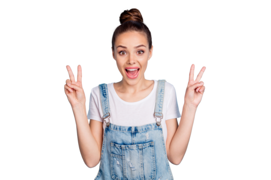 Portrait of cheerful girl screaming making v-signs wearing white t-shirt denim jeans overall isolated over blue background