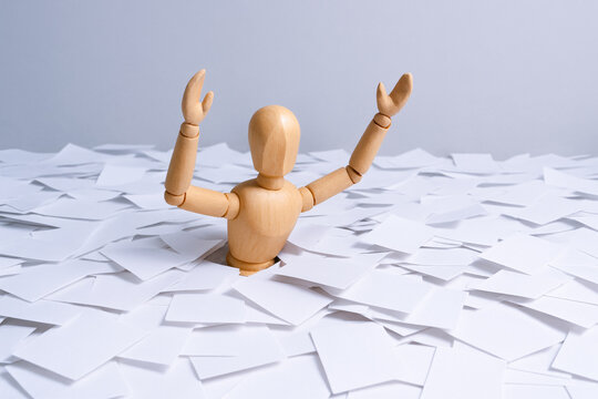 Conceptual wooden figures illustrate concepts of pressure and judgment as figure raises arms among scattered papers - Powered by Adobe