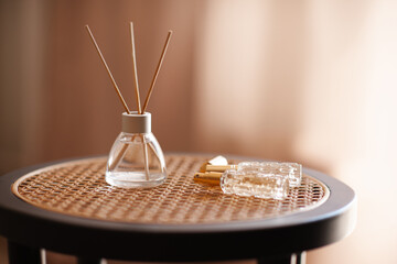 Liquid home perfume in glass bottle with bamboo sticks on rattan table in room close up....