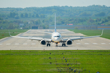 Airplane preparing for takeoff on a sunny day at a spacious airport runway surrounded by lush green...