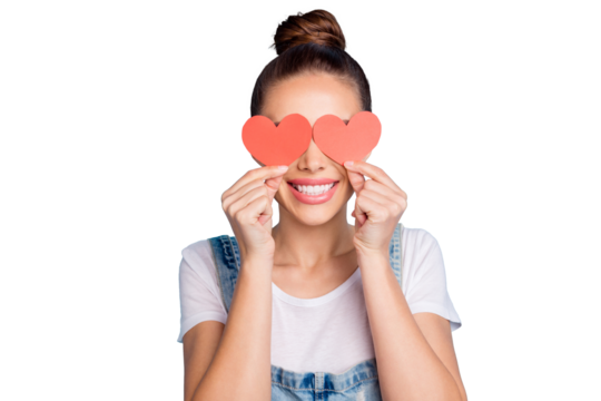 Close up photo of lovely girl hiding her eyes with paper card heart wearing white t-shirt denim jeans overalls isolated over blue background