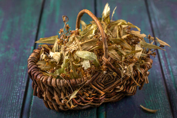 Dried herbs in a woven basket on a wooden surface