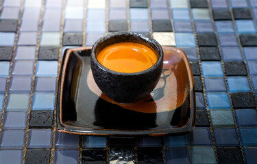 An espresso shot serving in classic black ceramic cup on amulticolored crystal  backgrounds.