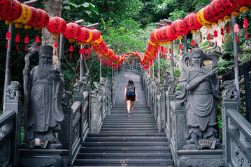 girl tourist walking up stairs to temple with red lanterns asia