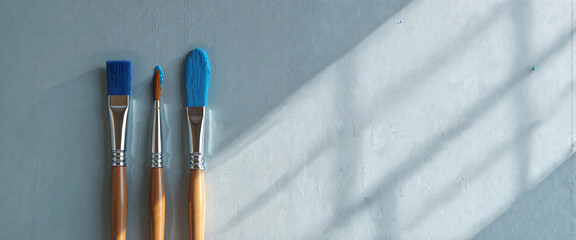 Three Paintbrushes with Blue Paint on Light Gray Background Artistic Supplies Studio Shot