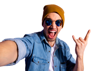 Self portrait of trendy stylish cheerful rude screaming guy taking selfie showing you horned fingers rock sign wearing brown cap denim isolated over purple vivid color background
