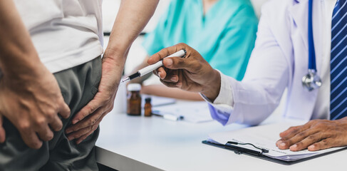 Doctor is diagnosing butt pain and hemorrhoids treatment of male patient in exam room at hospital.