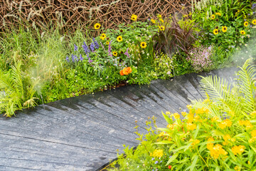Walkway in flower garden in summer time. Colourful Flowerbeds in a good care maintenance landscapes...