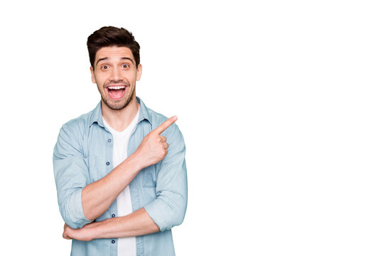 Photo of cheerful positive brown haired cute man pointing at empty space expressing shocked emotions excited ecstatic isolated over green vivid color background