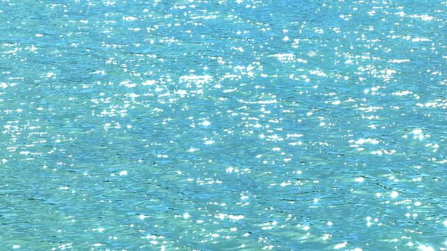 A top-down view of a tropical sea, where the sunlight reflects off the gentle waves, illuminating the serene, transparent blue waters with a radiant glow.
