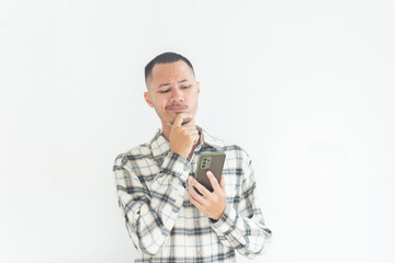 Young Adult man holding phone wearing flannel shirt showing thinking gesture. Hip on chin