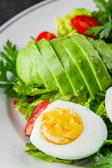 Salad avocado, boiled egg, tomato, green leaf lettuce, vegetable dish fresh gourmet food background on the table rustic food top view copy space vegetarian food